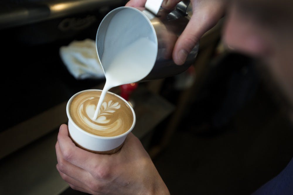 Lansing resident Peter Hochstedler pours milk into a latte to create a floral design on Nov. 5, 2016 at Strange Matter Coffee in Lansing. Hochstedler has been working at Strange Matter Coffee since the shop opened in 2014.