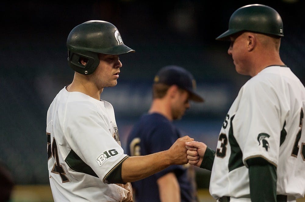 <p>Freshman catcher/infielder Chad Roskelly fist bumps head coach Jake Boss Jr. April 14, 2015, during the game against Michigan at Comerica Park in Detroit. The Spartans defeated the Wolverines, 4-2. Allyson Telgenhof/The State News.</p>