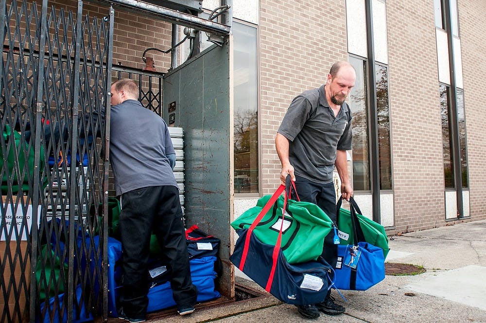 From left, Lansing residents Eric Woods and John Watson transport bags of ballots from the basement of East Lansing City Hall, 410 Abbot Road, on Nov.5, 2012. Woods and Watson were in charge of collecting and distributing voting materials in preparation for the election. James Ristau/The State News