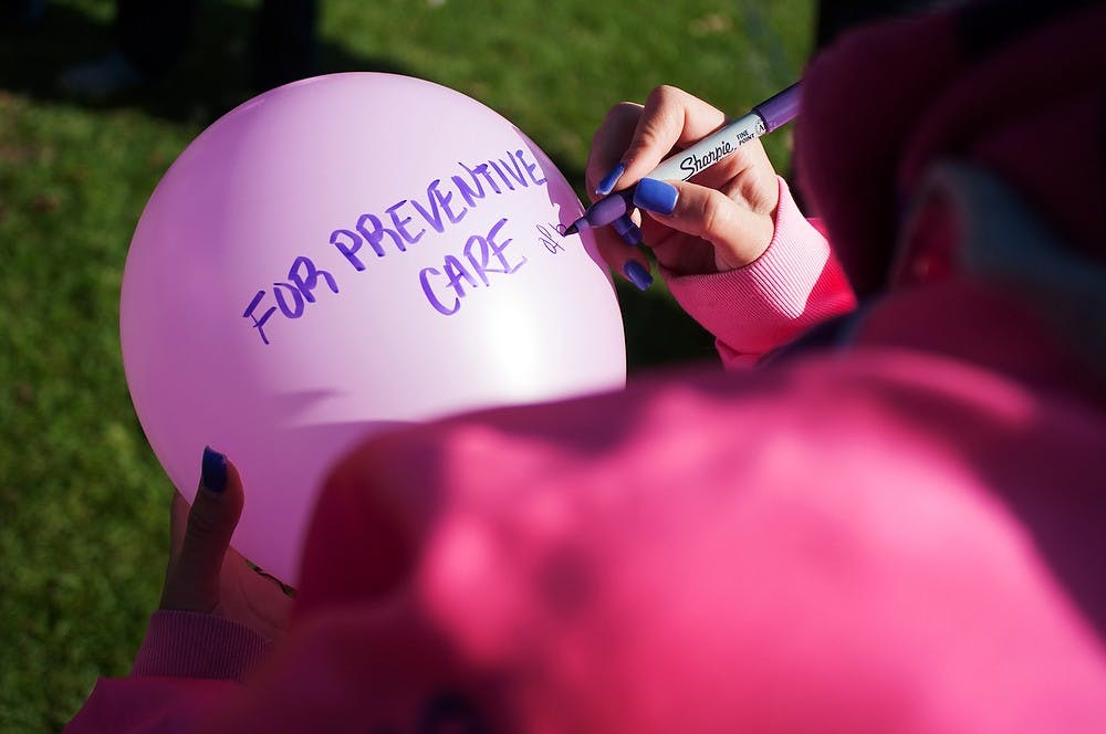 	<p>East Lansing resident Matea Caluk writes a message on a pink balloon on Oct. 27, 2013, at the rock on Farm Lane. The West Michigan Association of Sigma Lambda Gamma released 45 pink balloons with messages for Breast Cancer Awareness Month. Georgina De Moya/The State News</p>