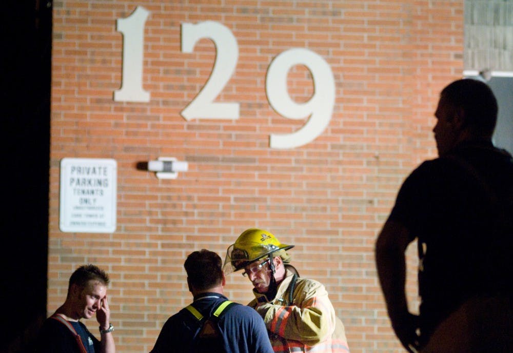 	<p>East Lansing firefighter Jim Hudson, center, talks to fellow firefighter Jeff Lund, left center, as first responders clean up and investigate a fire that erupted late Monday night at 129 Burcham Apartments. Three of 12 units were damaged in the fire but no one was injured, according to a firefighter on scene.</p>