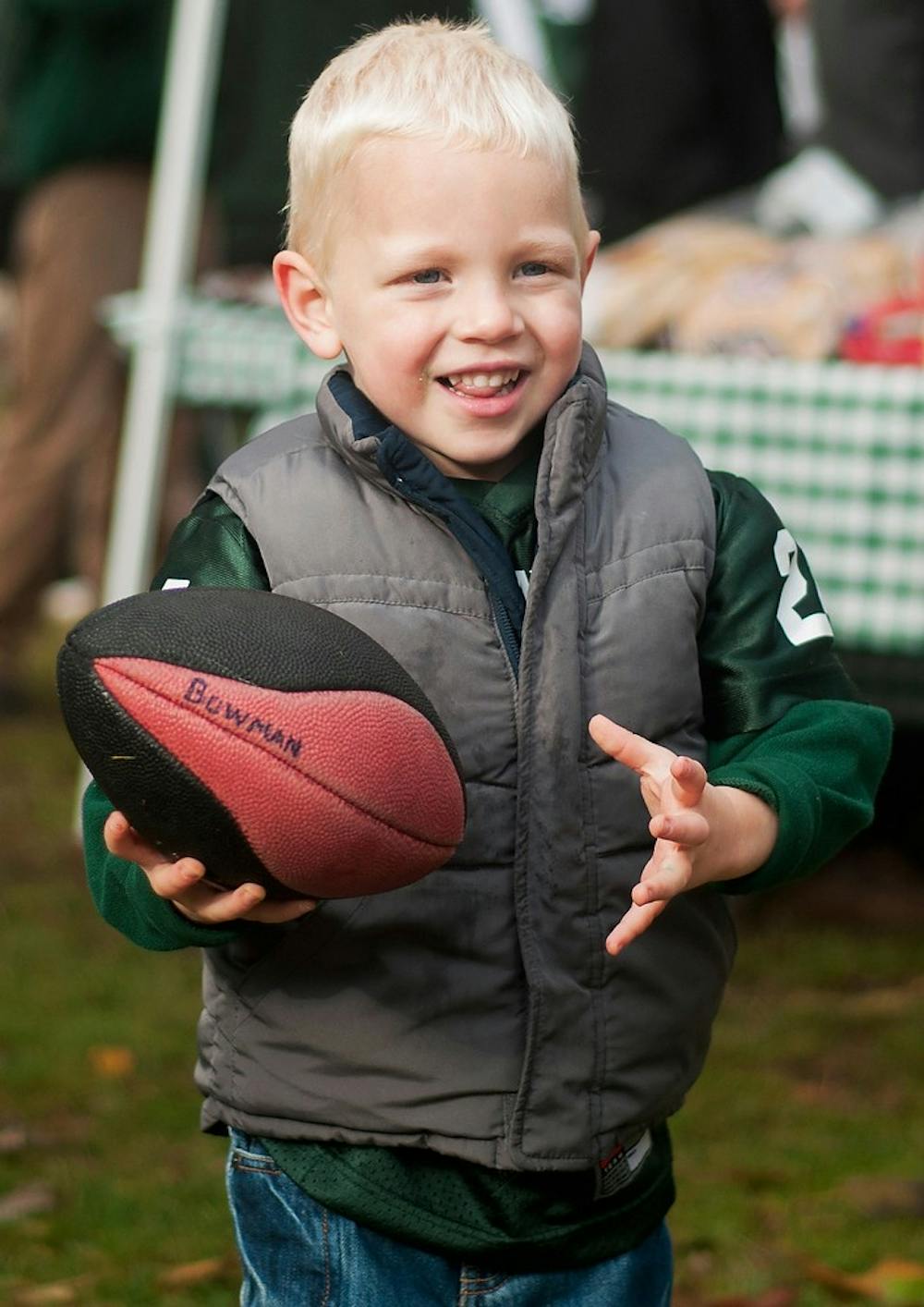 	<p>Howell, Mich., resident Tate Bowman, 3, plays with a football on Nov. 2, 2013, near Auditorium Road. Thousands of fans tailgated across campus before the game against Michigan. Georgina De Moya/ The State News</p>
