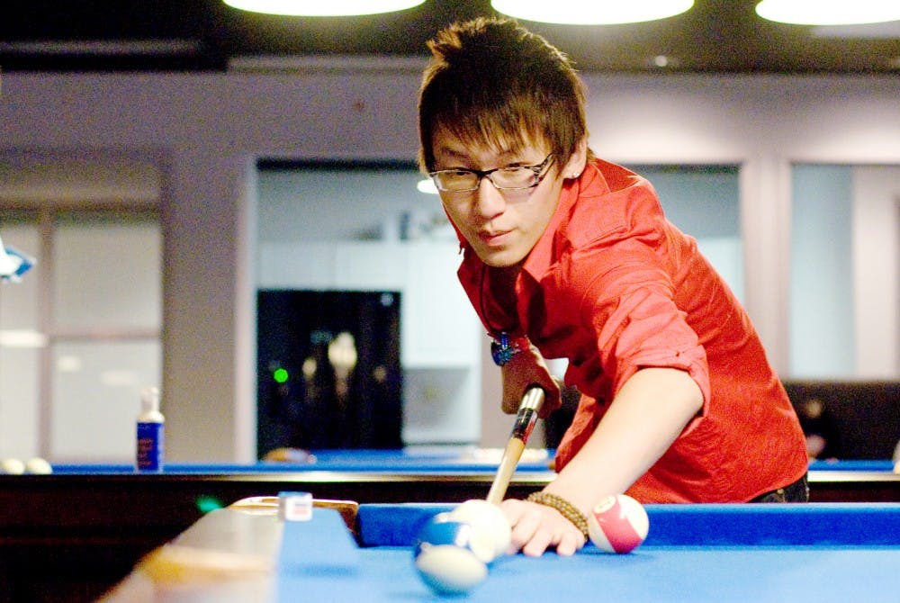 Management junior and CEO and general manager of Triple-T, LLC Eason Chen prepares to strike a ball during a game of pool Wednesday night at the company's newly opened game lounge, karaoke and billiards hall Heart Beats, 301 M.A.C. Ave. Justin Wan/The State News