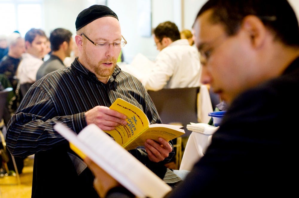 Lansing resident David Shelvey, left, reads from a prayer book on Friday evening to celebrate the Jewish holiday Passover as he sits with a table with civil engineering doctoral student Mohamed Rhimi at MSU Hillel, of 360 Charles Street. Justin Wan/The State News