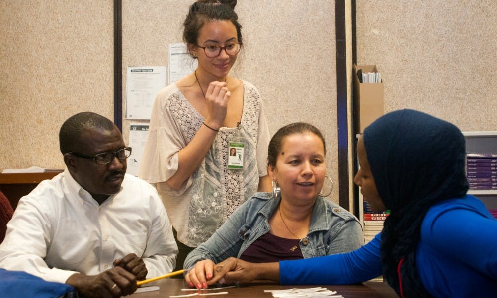<p>From left to right, sitting at the table, Lansing resident Ahmed Jerou, Lansing resident Flora Sandoual Aguilar, and volunteer Hannatu Sadiq, a human development and family studies sophomore, work on an activity for an ESL class while anthropology senior Marissa Marinello, standing, watches over on Oct. 14, 2015, at the Schmidt Community Center, 5825 Wise Rd, in Lansing. Marinello started at the Refugee Development Center as a volunteer and is now a lead teacher for a beginner level adult ESL class.</p>