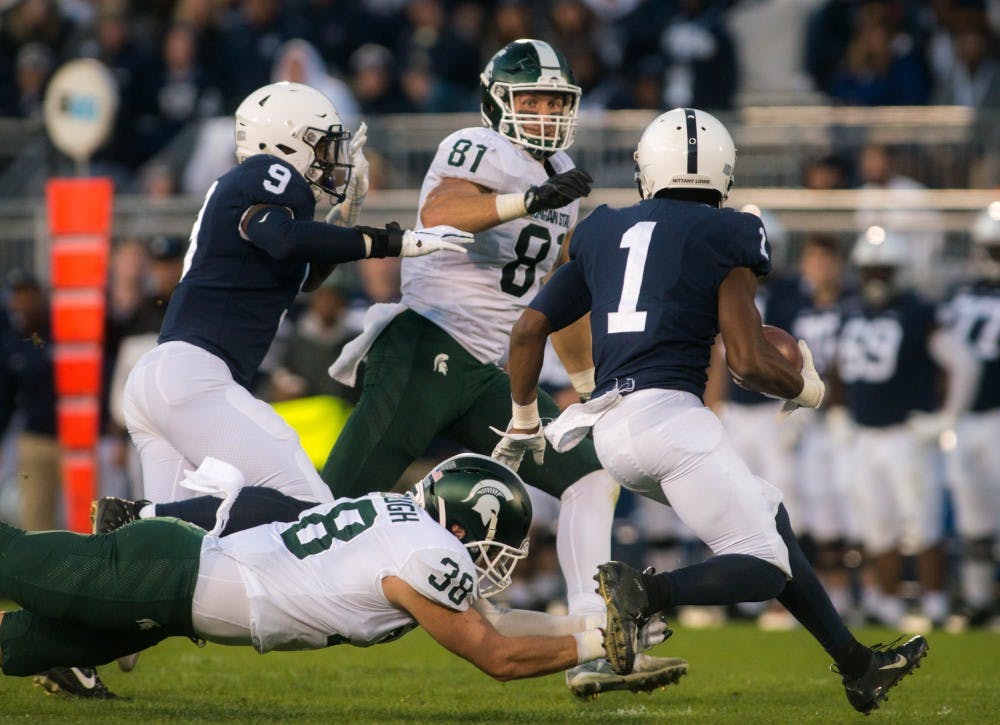 <p>Former senior tight end Matt Sokol (81) and former senior linebacker Byron Bullough (38) tackle Penn State wide receiver KJ Hamler (1) during the game against Penn State at Beaver Stadium on Oct. 13, 2018. The Spartans defeated the Nittany Lions 21-17.</p>