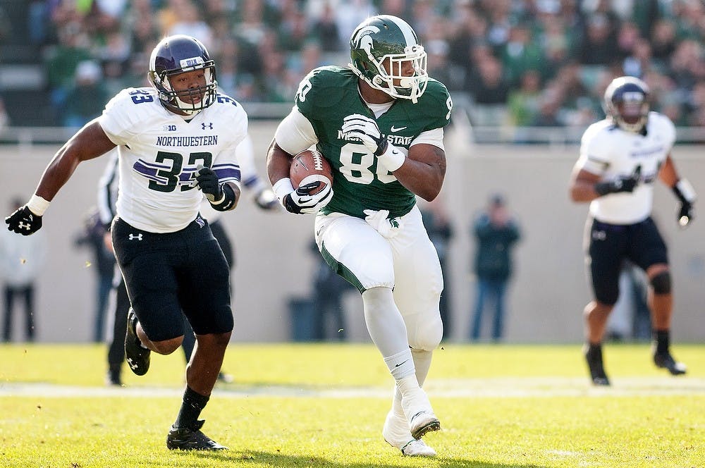	<p>Junior tight end Dion Sims runs down the field after receiving a long pass in the first half of the game with Northwestern linebacker David Nwabuisi trailing him. The Spartans fell to the Wildcats, 23-20, Nov. 17, 2012, at Spartan Stadium during senior day. Justin Wan/The State News</p>