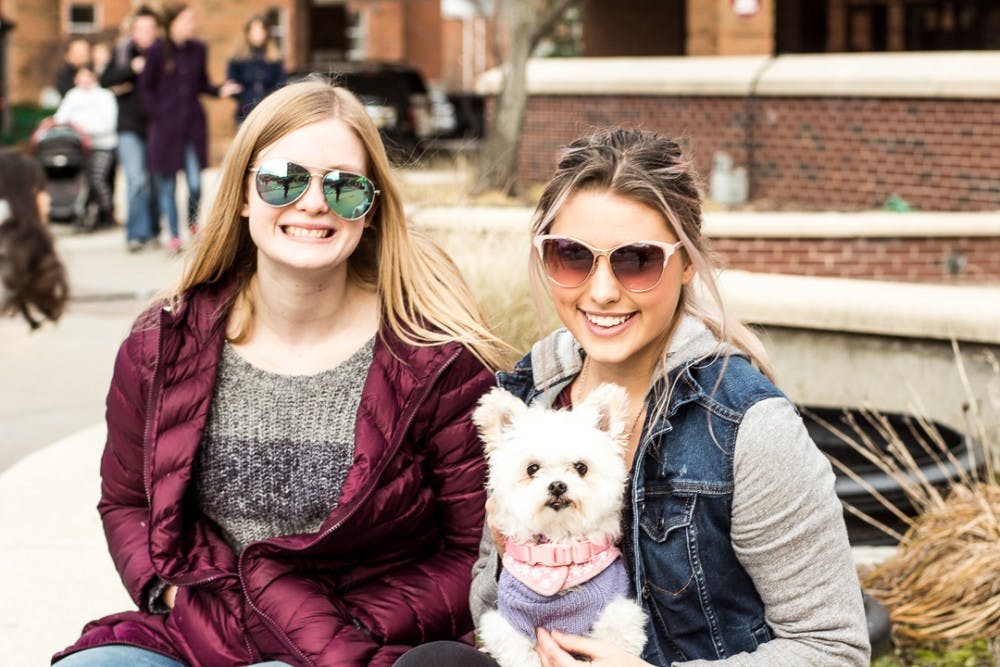 From left to right, Lansing residents Zoe McClintic and Felicia French  smile with their dog, Violet during the annual Winter Glow Festival on Dec. 2, 2017 at Ann St. Plaza. The free festival featured carriage rides, music, an outdoor holiday farmers market, marshmallow roasting, and other seasonal activities. 