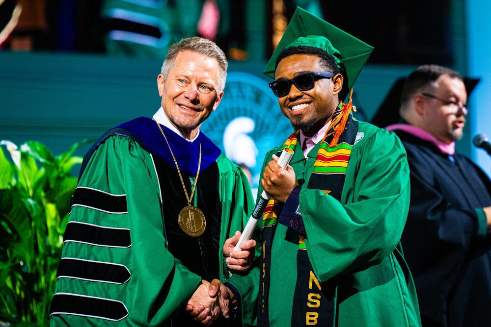 An alumnus is congratulated by MSU president Kevin Guskiewicz during the fall 2024 commencement ceremony at the Breslin Center on Dec. 14, 2024.