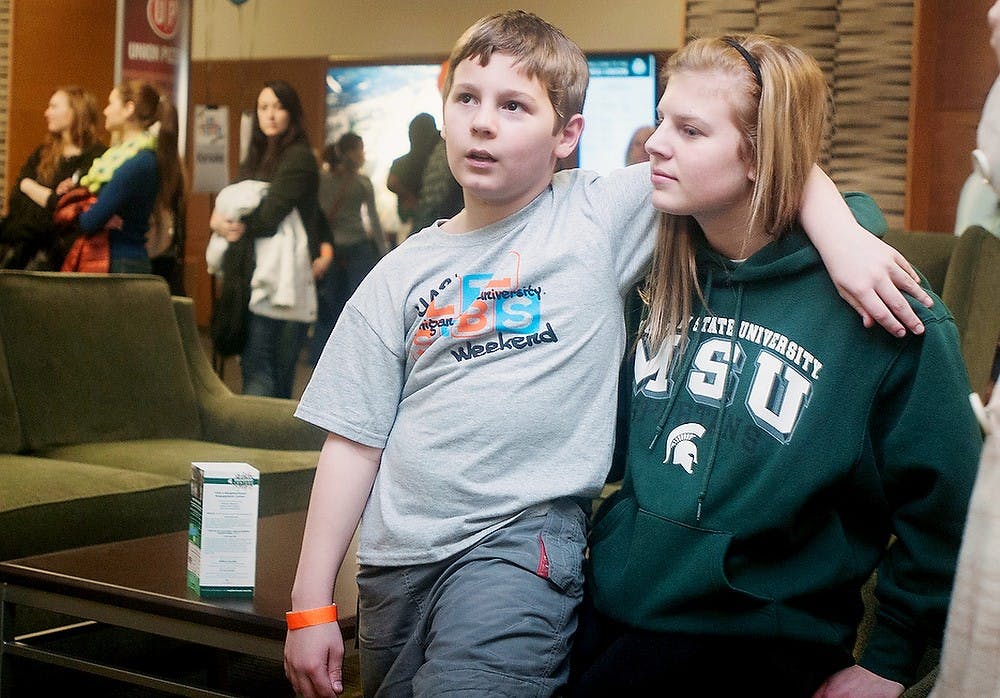 	<p>Grand Rapids resident Nick Schlee, 9, sits on the lap of his sister, prenursing freshman Kali Schlee, while waiting in line for a balloon animal during the <span class="caps">MSU</span> Lil Sibs Weekend registration events on Friday, Feb. 8, 2013, in the Union. The sibling pair participated in the karaoke, line dancing and life-sized candy land events hosted by the University Activities Board.</p>