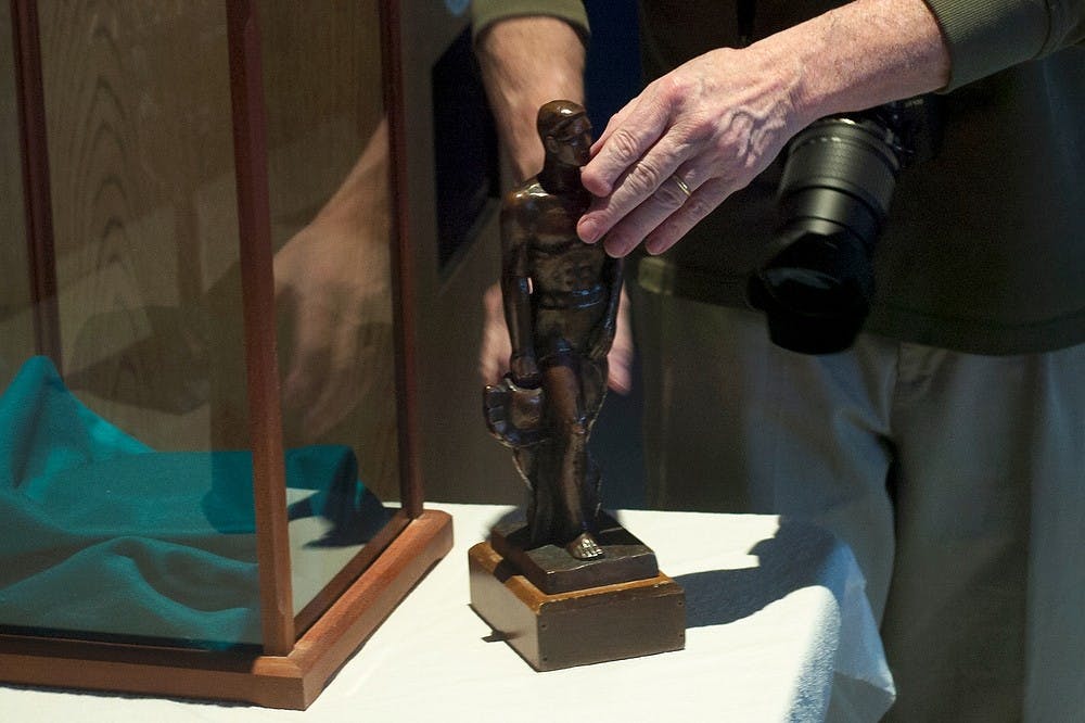 <p>Lansing resident Bill Castanier takes a 60-year-old replica of Sparty out of its case for a program put on by the Historical Society of Greater Lansing April 3, 2014, at Lansing City Hall. The replica is a 14-inch bronze Sparty and is the only copy by Sparty's original sculptor, Leonard Jungwirth. Emily Jenks/The State News</p>