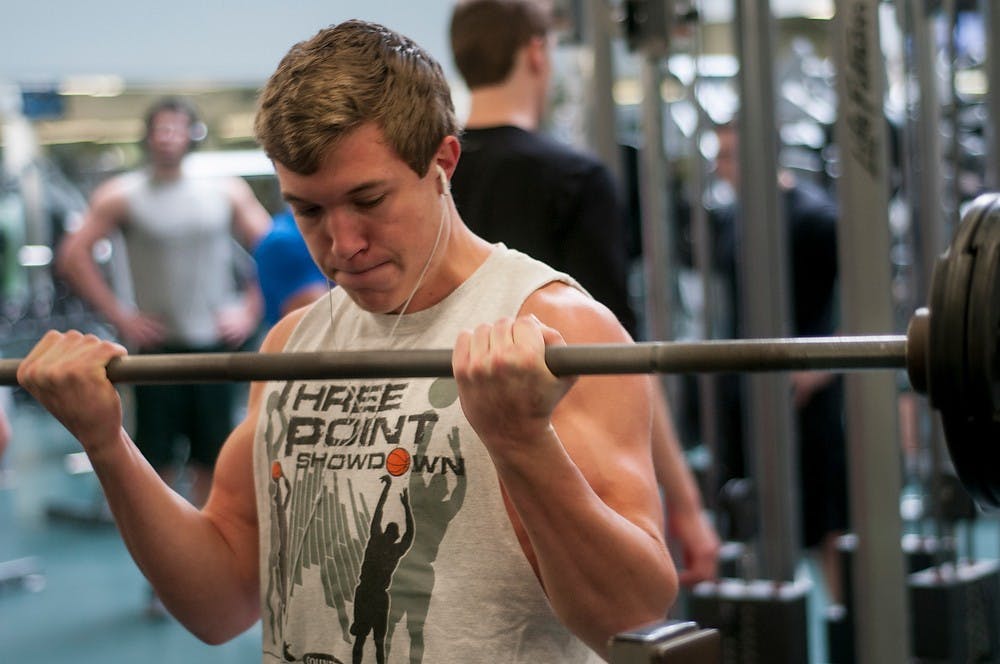 <p>Mechanical engineering sophomore Conner Archey lifts some weights on Dec. 3, 2014, at IM Sports West. "Working out most definitely relieves me from a lot of the stress from finals week," Archey said. "I work about for about an hour, 4 times a week." Raymond Williams/The State News</p>