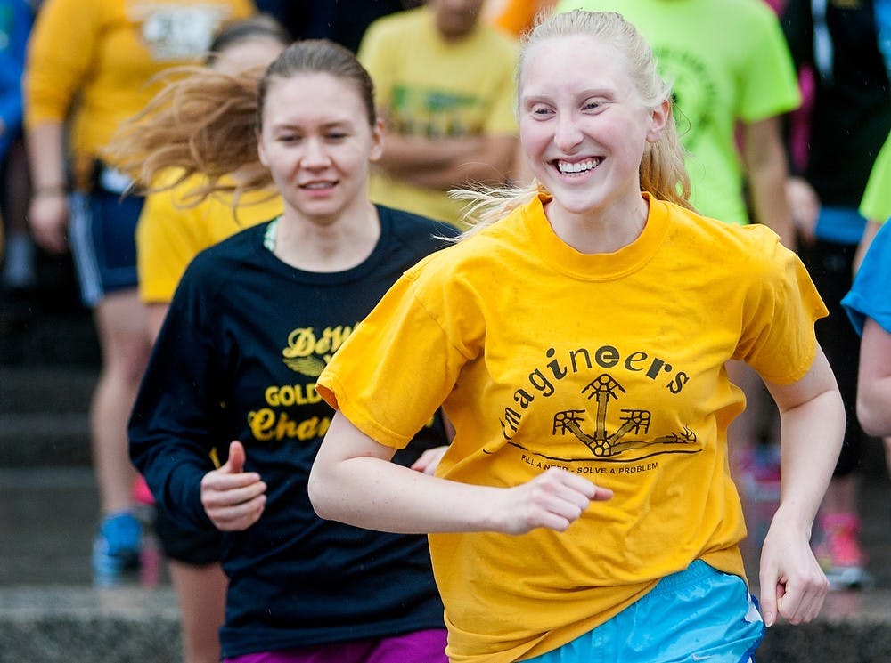 	<p>Physics sophomore Tarah Thompson, right, smiles as she runs with psychology sophomore Ustina Shives at the starting point of the Spartans Run for Boston April 17, 2013, outside IM Sports-West. The run was a localized event to show solidarity for the explosion at the Boston Marathon April 15, 2013. Event organizers asked students and participants to dress in yellow or blue, the colors of the Boston Marathon. Justin Wan/The State News</p>