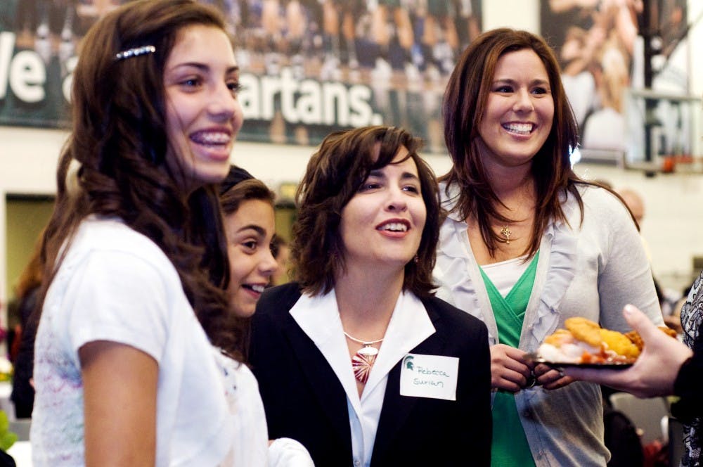 	<p>Award recipient Rebecca Surian, center, stands in a circle with her daughters, from left, Victoria, 14, and Catherine, 10, and her co-worker, Linda Conradi, before the 2011 Jack Breslin Distinguished Staff Award ceremony Monday at Breslin Center. The group laughed after shown a photograph of Rebecca Surian at her 1990 <span class="caps">MSU</span> graduation. Surian is the director of development in the College of Music and was one of six staff members receiving awards. </p>