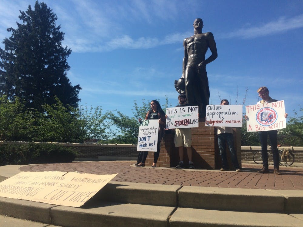 <p>Members of the Indigenous Graduate Student Collective protest cultural appropriation at Spartan Statue on August 7, during the 2015 NOAC. Matt Argillander/ The State News</p>