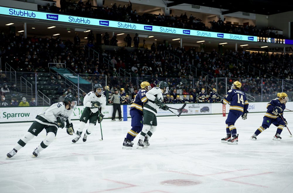 <p>Notre Dame senior Spencer Stastney getting caught up with Michigan State sophomore A.J. Hodges as they chase the puck on Feb. 18, 2022. Spartans lost 2-1 against Notre Dame.</p>