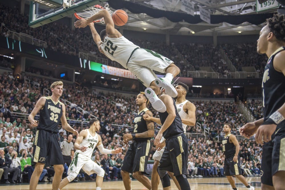 Sophomore guard Miles Bridges (22) swings from the rim after dunking the ball during the first half of the men's basketball game against Purdue on Feb. 10, 2018 at Breslin Center. The Spartans trailed the Boilermakers at the half, 36-31. (Nic Antaya | The State News)