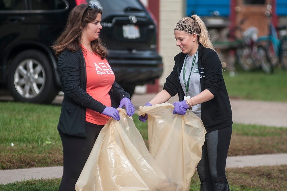 <p>Social relations and policy junior Athena Antonis, left, and nutritional sciences junior Kierstin Sanch help the Community Relations Coalition clean up the residential areas of East Lansing on Sept. 28, 2014, by East Lansing City Hall on Park Lane. Raymond Williams/The State News</p>