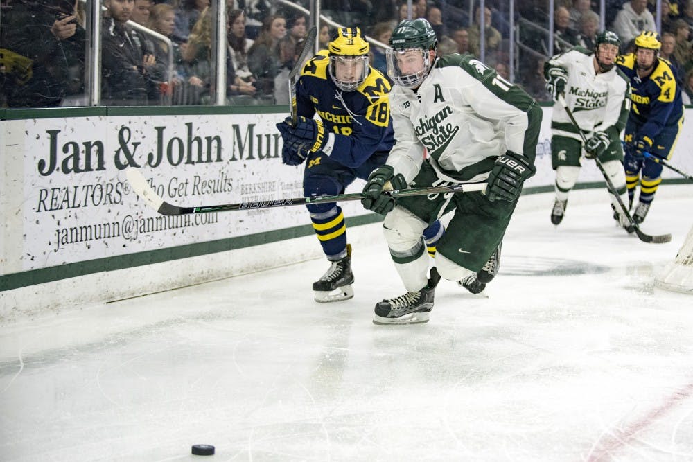 Senior defense Rhett Holland (11) attempts to gain control of the puck as he is defended by Michigan forward Adam Winborg (18) during the second period in the game against on Jan. 21, 2016 at Munn Ice Arena. The Spartans were defeated by Wolverines, 2-3.
