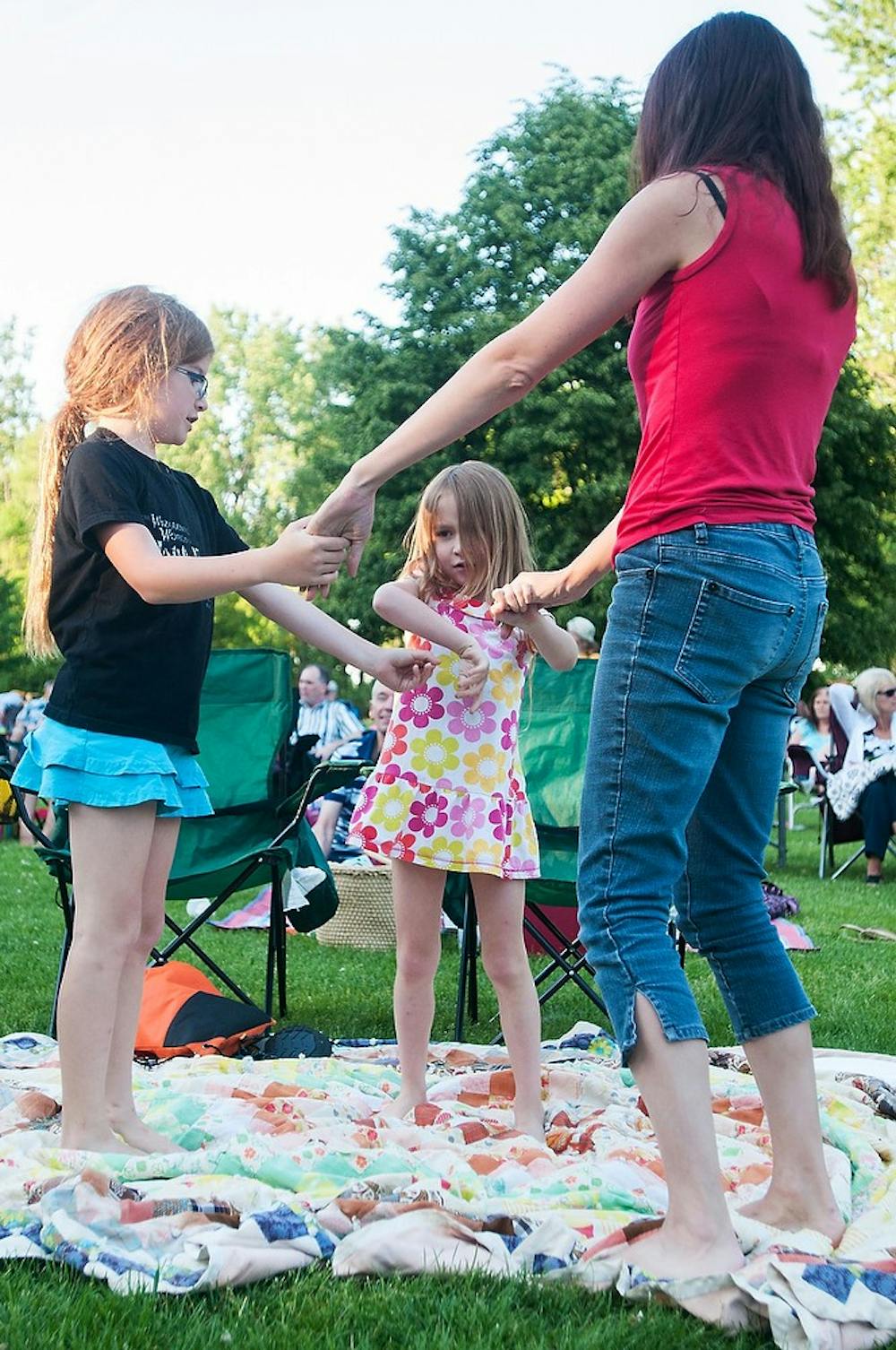 <p>East Lansing resident Staci Stoddard, right, dances with her daughters Elizabeth Stacey, 6, and Kate Stacey, 9, June 6, 2014, outside the Lake Lansing Band Shell in Lake Lansing Park South in Meridian Charter Township, Mich. Music for the event was provided by Lansing-based musical group, Soulstice. Corey Damocles/The State News</p>