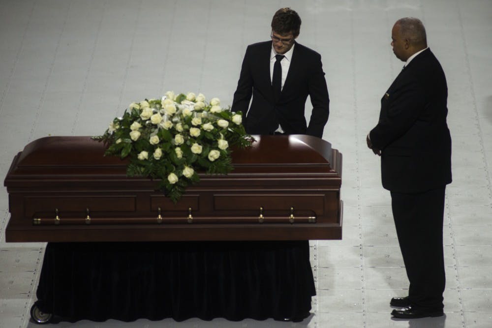 Tyler Walsh stands beside the casket of his grandfather Ron Mason before carrying him off the ice after the funeral service on June 16 at Munn Ice Arena. 