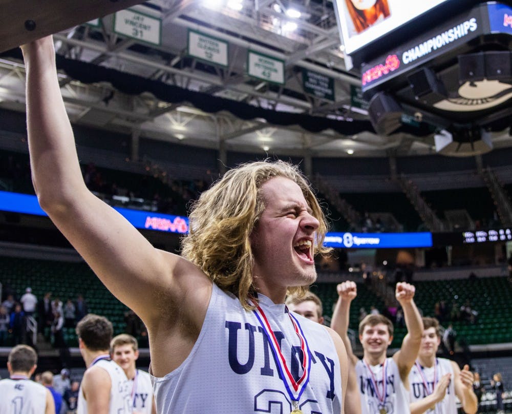 Senior center Bryce Lanser holds up the trophy after his team's win in the MHSAA Division 2 boys basketball finals March 16, 2019, at Breslin Center. The Unity Christian Crusaders defeated the River Rouge Panthers, 58-55.