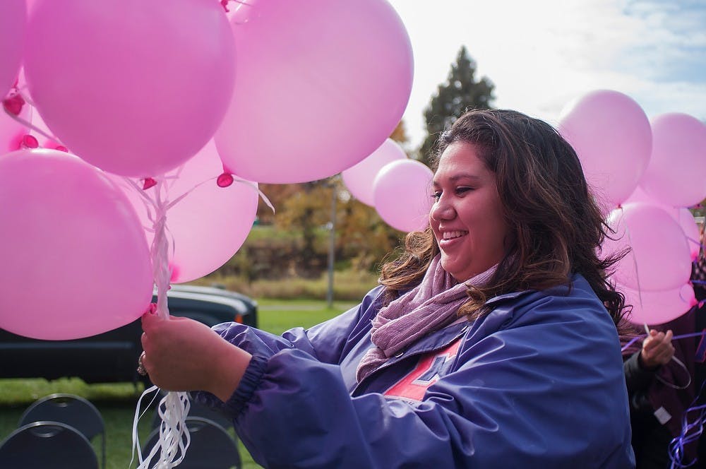 	<p>Kalamazoo resident Elizabeth Martinez untangles pink balloons on Oct. 27, 2013, at the rock on Farm Lane. The West Michigan Association of Sigma Lambda Gamma released 45 pink balloons with messages for Breast Cancer Awareness Month. Georgina De Moya/The State News</p>