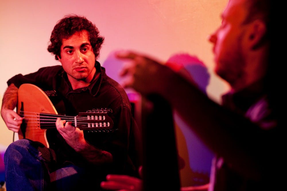 Electric oud player Igor Houwat looks to his band mate and percussionist Ty Forquer as they perform Saturday evening at Scene Metrospace. The band the duo plays in, Wisaal, is formed primarily by Michigan State music students, past and present. Matt Hallowell/The State News