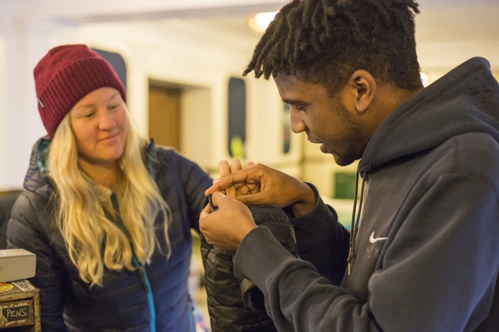 Left, Ojai, Cali. resident Cheney Caldwell helps a student fix a hole in his jacket during Patagonia's Worn Wear College Tour March 31, 2017 at MSU Auditorium. Cheney is the assistant tour manager. "The last thing you're going to do is fix a $300 jacket," Cheney says. Patagonia hopes to decrease the amount of clothing that is tossed into landfills by teaching people how to fix their own clothes or find alternative ways to use them.
