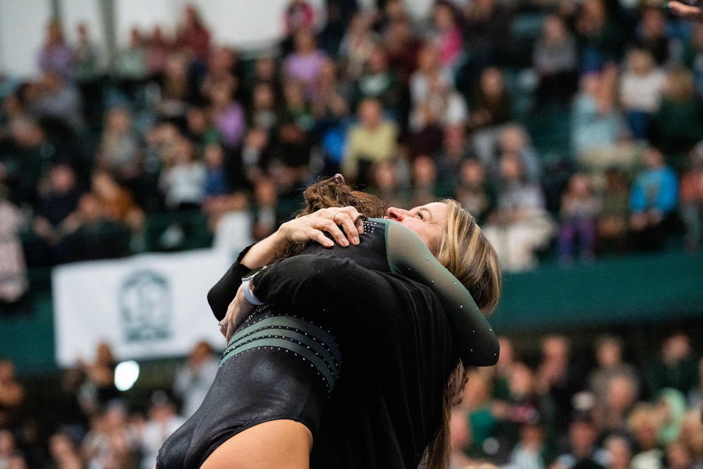 <p>Sophomore Sage Kellerman runs into a hug after completing a routine during a meet against the University of Maryland at Jenison Field House on Feb. 18, 2024.</p>