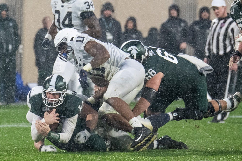 <p>Senior quarterback Brian Lewerke (14) is tackled during the game against Penn State Oct. 26, 2019, at Spartan Stadium. The Spartans fell to the Nittany Lions, 28-7.</p>