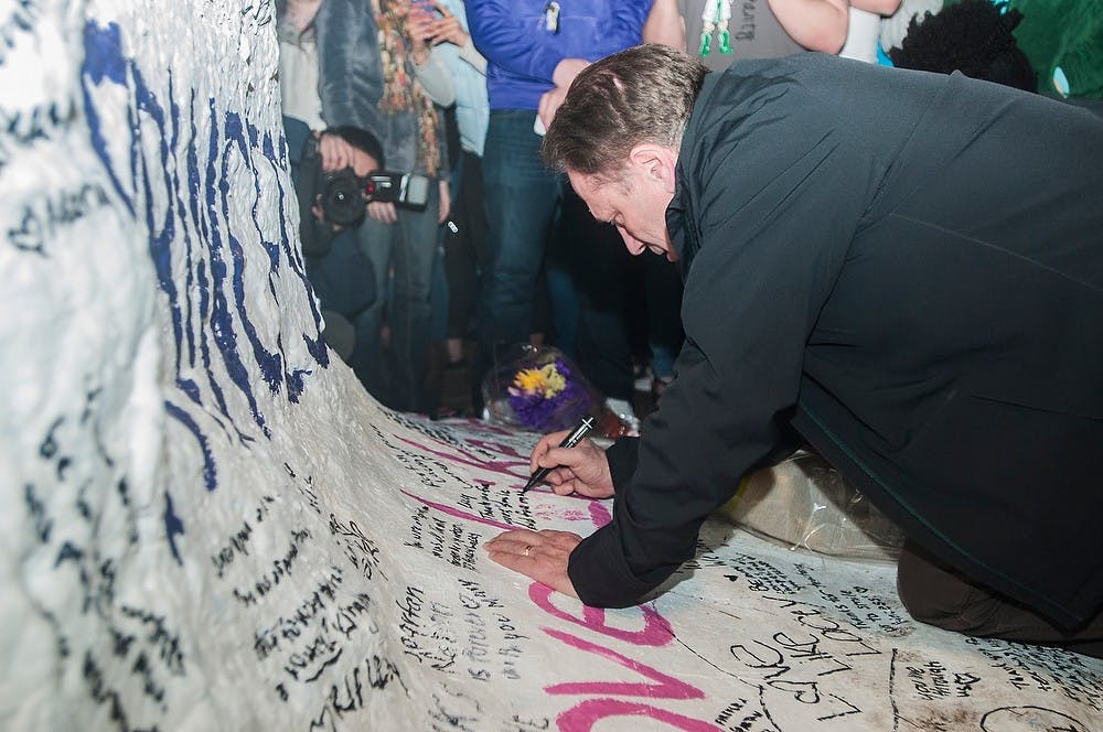 <p>Men's basketball head coach Tom Izzo signs the Rock on Farm Lane on April 9, 2014, in remembrance of Lacey Holsworth at her memorial. Holsworth was a good friend of senior forward Adreian Payne and passed away April 8 after a battle with cancer. Erin Hampton/The State News</p>