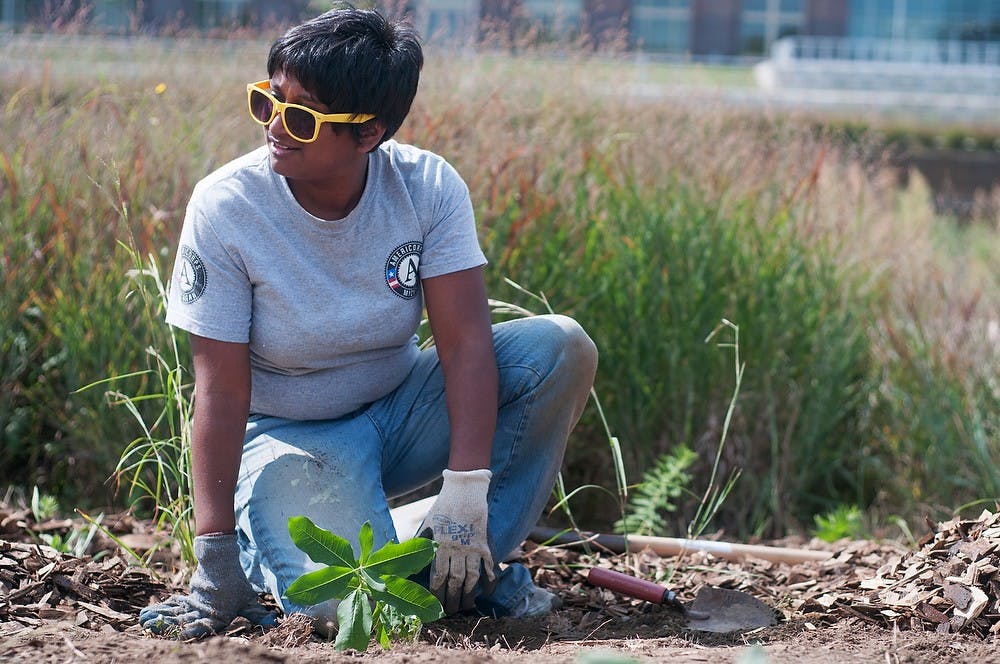 	<p>Lansing resident Michelle Adams plants flowers for the National Day of Service on Sept. 11, 2013, behind the Lansing City Market, in Lansing. Several other volunteers joined to beautify the area around the Lansing River Trail. Georgina De Moya/The State News</p>