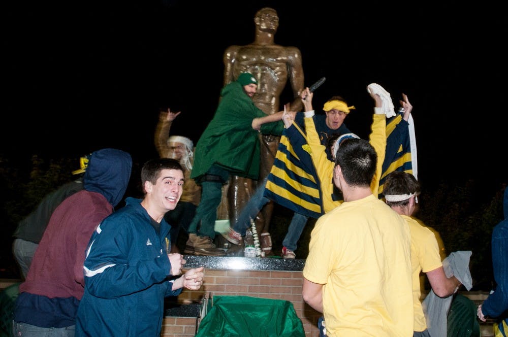 <p>Michigan students try to vandalize Sparty on Oct. 28, 2013, on Chestnut Road. They left after breaking a few of the MSU band's chairs. Khoa Nguyen/The State News</p>
