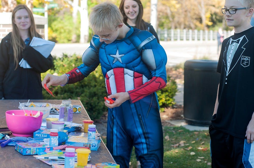 <p>Lansing resident Sam Wiley, 14, picks out prizes after a scavenger hunt held by Friends for Inclusive Sport on Oct. 26, 2014, near the Spartan Statue. Participants went to six iconic places on campus and took pictures at each in order to win their prize. Jessalyn Tamez/The State News </p>