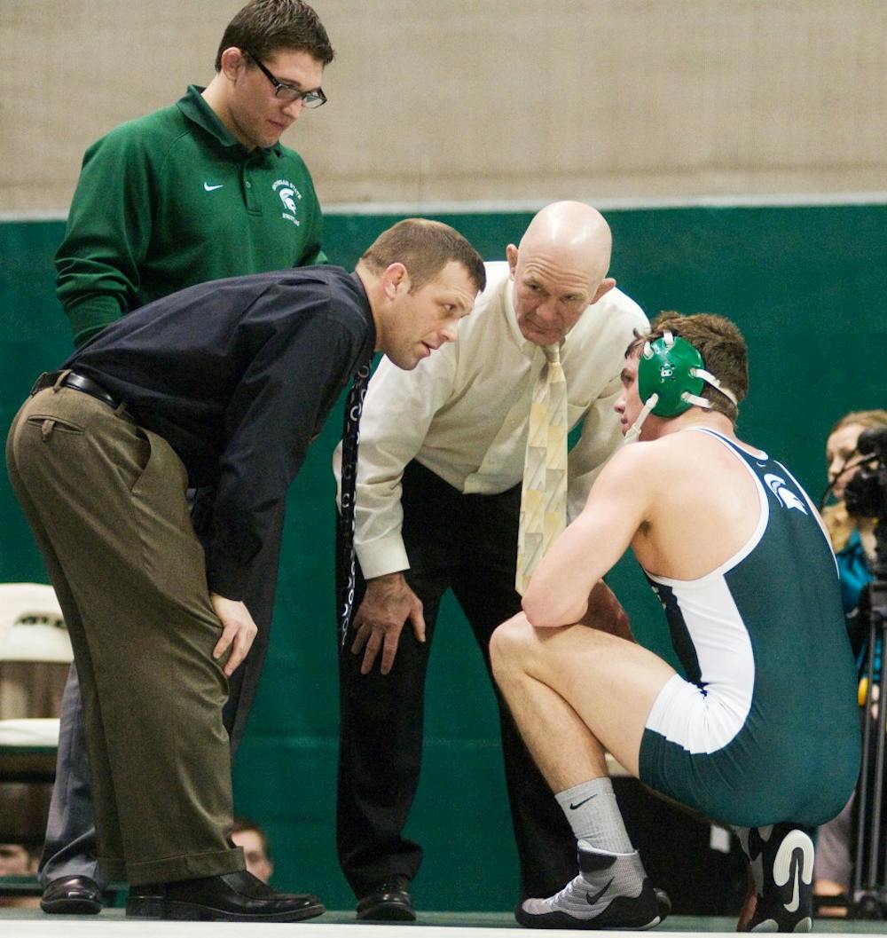 Junior Ian Hinton receives advice from coaches Roger Chandler and Tom Minkel Friday during his wrestling match at Jenison Field House.  Katy Joe DeSantis/The State News