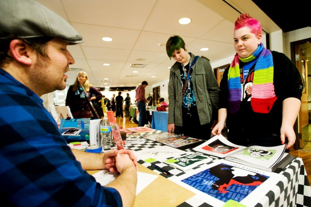 From left, Ann Arbor, Mich. comic artist Denver Brubaker talks with Bath, Mich. resident Maggie Cummings, 16, and biomedical laboratory operations sophmore Ryo Paclot Saturday morning at the LookOut! gallery inside Snyder-Phillips Hall. The two-day event brought comics artists, scholars and fans to MSU, home to the largest public collection of comic books, to celebrate the art of graphic storytelling. Justin Wan/The State News