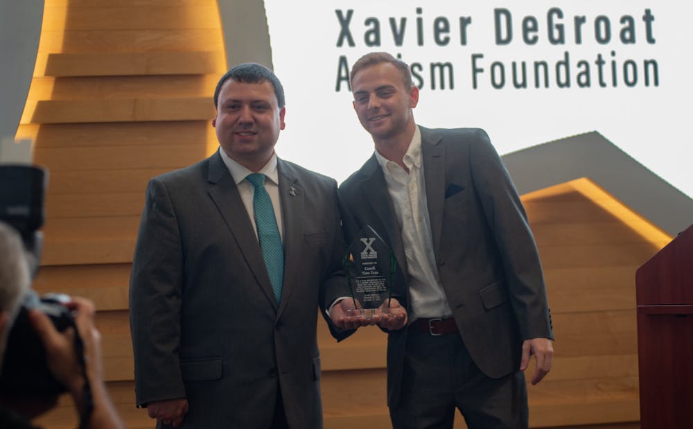 Xavier DeGroat hold's Head Coach Tom Izzo's award alongside Izzo's son Steven Izzo at the Spartan Sports Supports Autism Acceptance event on Oct. 19, 2021.