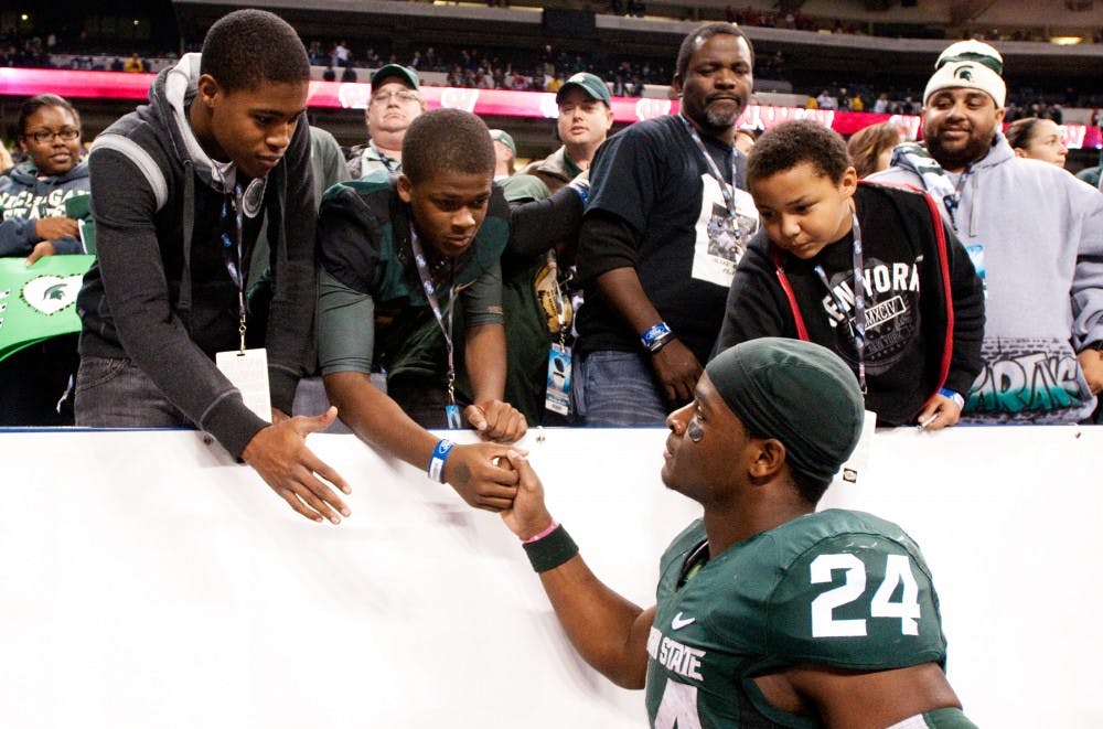 Sophomore runningback Le'Veon Bell greets family on the sidelines after the Spartans lost to the Wisconsin Badgers, 42-39, in the Big Ten Championship game on Saturday night at Lucas Oil Stadium in Indianapolis, Ind. Josh Radtke/The State News