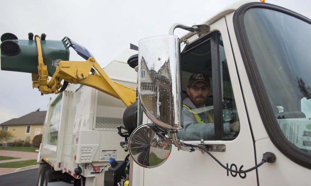 <p>East Lansing Department of Public Works worker Shaun O'Berry watches as trash is poured into his truck on Oct. 22, 2015 in East Lansing. </p>