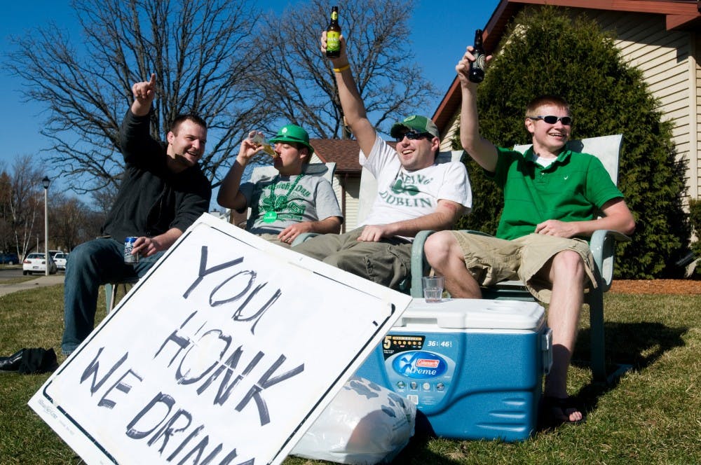 Ferris State University senior Matt Dobrowolski, from left, human resources senior Adam Carter, psychology senior Matt Carpenter and engineering senior Garrett Kerns raise their drinks after a car honked on Wednesday, St. Patrick's Day at their duplex at 1309 Albert. The group started at noon, and had a sign up that said 'You honk, we drink." Lauren Wood/The State News