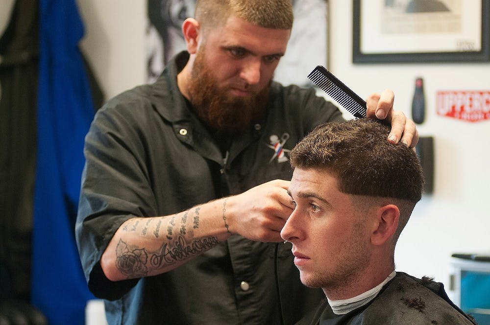 <p>Owner/barber Grant Foley cuts applied engineering  sciences junior Brad Perri's hair Oct. 13, 2014, at Grand River Barber Company in East Lansing. Students are able to get discounted haircuts Monday though Wednesday. Aerika Williams/The State News</p>
