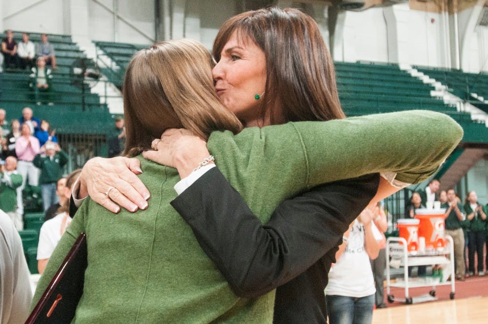 Volleyball head coach Cathy George hugs former outside hitter Jenilee Rathje while being honored for being named an AVCA third team All-American before the game against Purdue on Friday, Sept. 21, 2012. Family and friends attended the game to cheer for Rathje. Julia Nagy/The State News