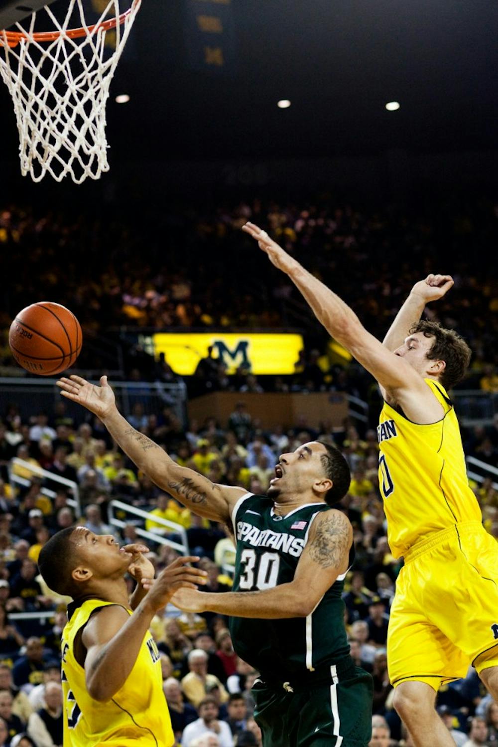 Redshirt senior guard Brandon Wood looks for a layup under heavy defensive pressure from Michigan guards Trey Burke and Zack Novak Tuesday night at Crisler Area. The Spartans fell to the Wolverines 59-60. Matt Hallowell/The State News