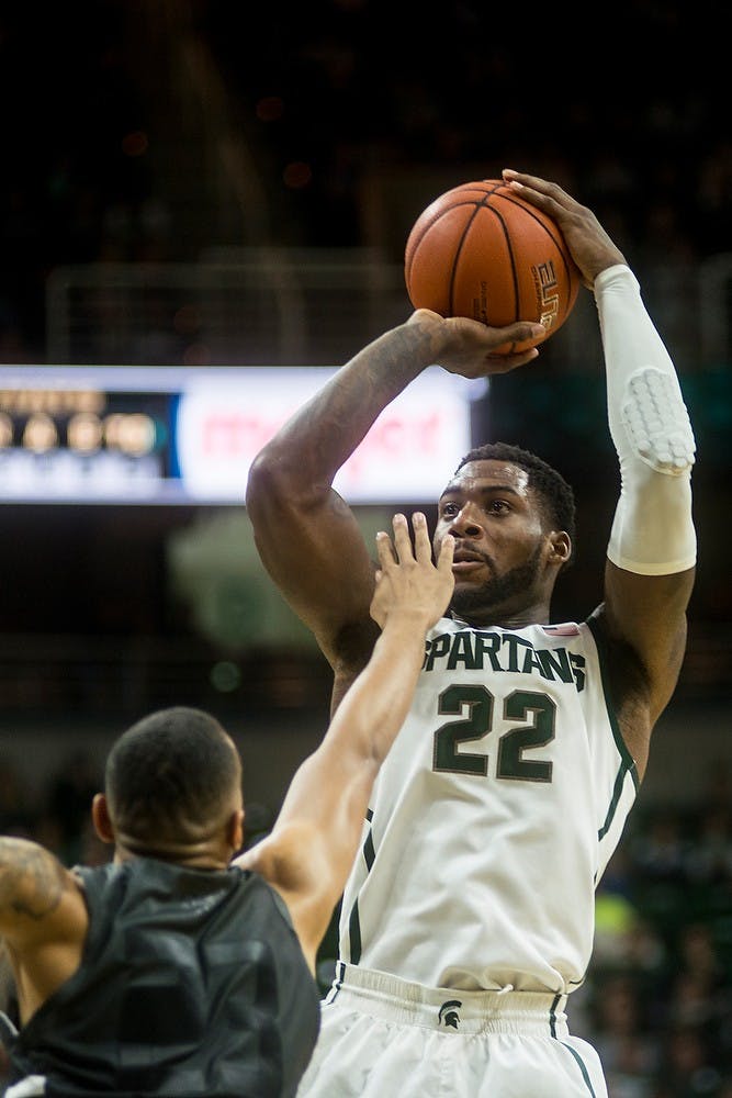 <p>Senior forward/guard Branden Dawson attempts a point over Oakland forward Tommie McCune Dec. 14, 2014, during a game against Oakland at Breslin Center. The Spartans were leading the Golden Grizzlies at halftime, 44-31. Erin Hampton/The State News</p>