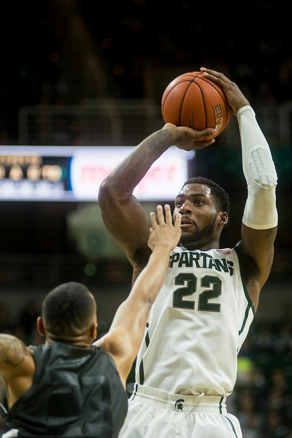 <p>Senior forward/guard Branden Dawson attempts a point over Oakland forward Tommie McCune Dec. 14, 2014, during a game against Oakland at Breslin Center. The Spartans were leading the Golden Grizzlies at halftime, 44-31. Erin Hampton/The State News</p>