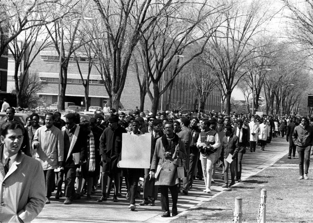 This photograph shows African-American students marching on campus. The text on the back reads: "Blacks 1960s. University Relations; African-Americans; Marches." Photo Courtesy MSU Archives. 