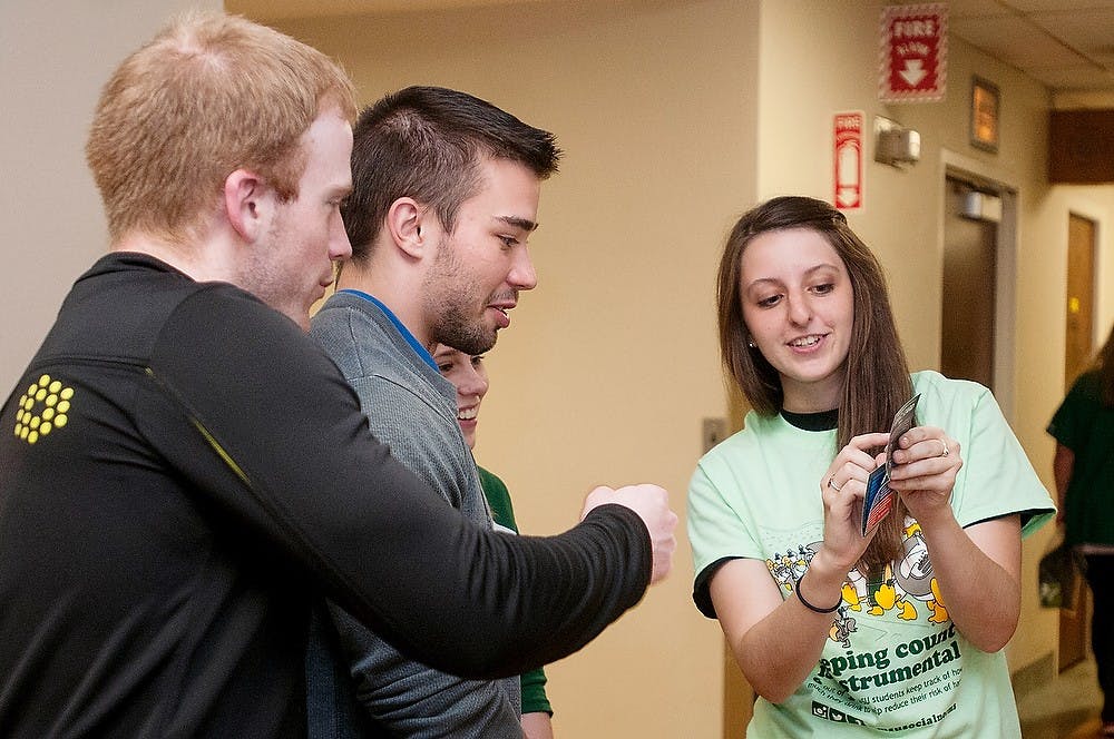 <p>From left, supply chain management senior Andrew Wallace and human biology junior Sean Young get information about drinking from special education senior Cari Otis on Sept. 30, 2014, at Olin Health Center. Olin Health Center celebrated their 75th anniversary. Aerika Williams/State News </p>