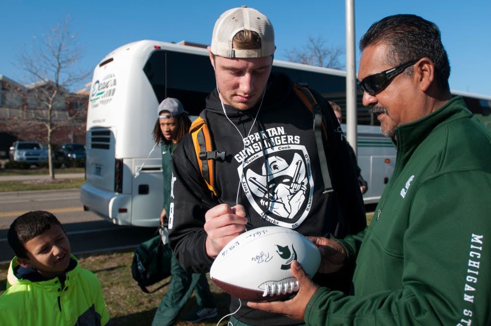 Senior quarter back Connor Cook signs a football for Delta Township, Mich., resident Alfredo Sifuentes on Dec. 6, 2015 outside of the Duffy Daugherty Football Building. The Spartan football team is arriving from winning the Big Ten championship game in Indianapolis.