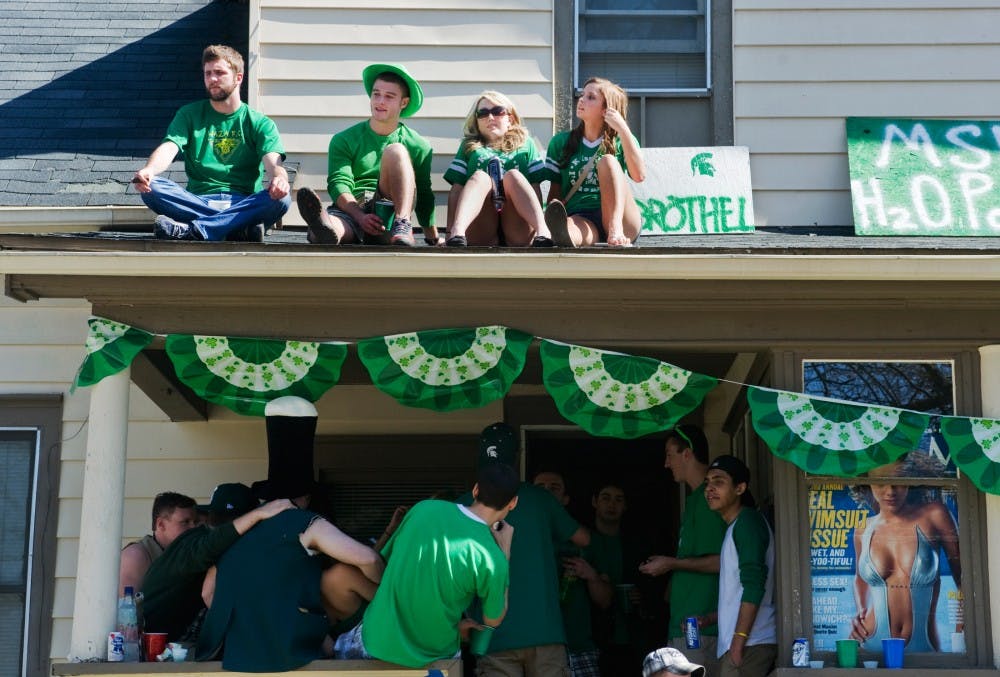 Top left, philosophy junior Ryan Lemasters, education junior Eric Gates, per-nursing sophomore Morgan White and no-preference freshman Emily Wesley sits on the roof of 204 Beal Street on Saturday afternoon during St. Patrick's Day. Thousands of students crowd the streets of East Lansing in celebration of the holiday rooted in the Irish traditions. Justin Wan/The State News